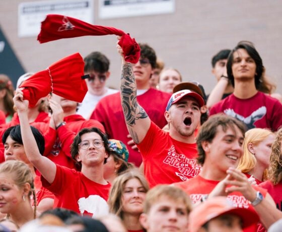 Two students cheer and wave tshirts in the air during a football game in Mountaineer Bowl.
