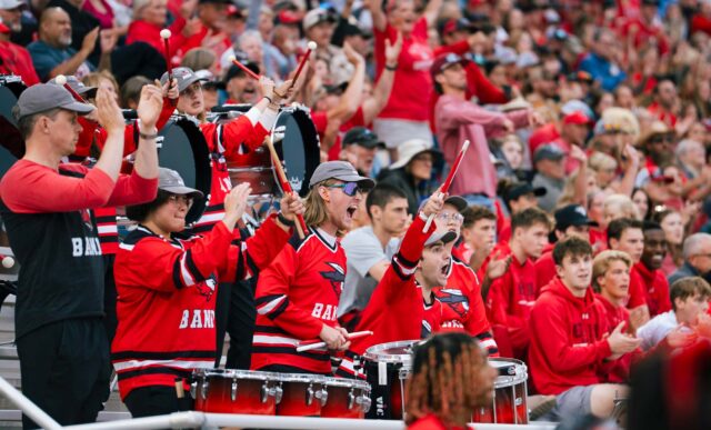 Students on the drumline cheer with excitement from their spot in the stands during a football game in the Mountaineer Bowl.
