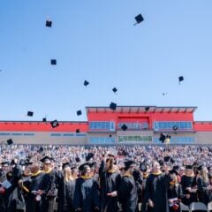 The class of 2024 throw their hats in the air in Mountaineer Bowl.
