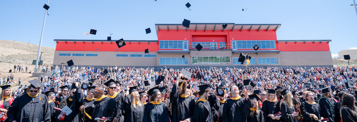 The class of 2024 throw their hats in the air in Mountaineer Bowl.