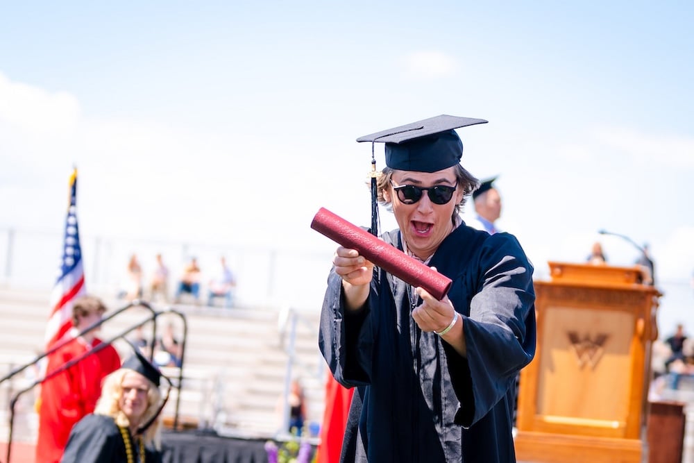 A graduate shows off his diploma as he walks back to his seat.