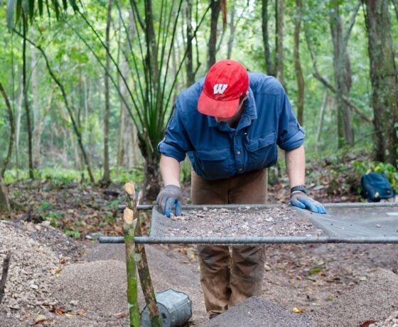 A student sifts through small rocks and sediment to check for artifact pieces during the Maya Archeaological Field School in Belize.