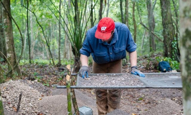 A student sifts through small rocks and sediment to check for artifact pieces during the Maya Archeaological Field School in Belize.