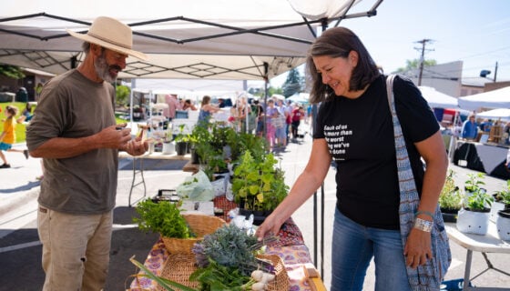 Leslie Taylor reaches for a bunch of greens at one of the booths at the farmer's market.