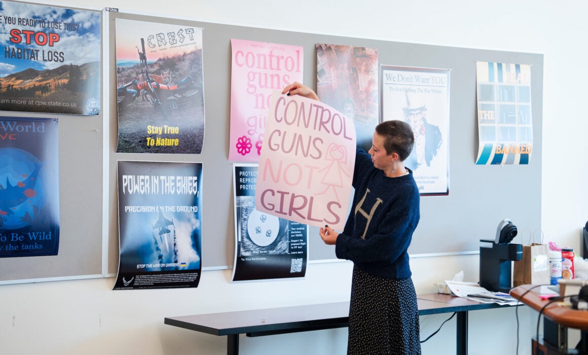 A graphic design student holds up a version of her poster she designed that says "Control guns, not girls," for the class to see during a critque.
