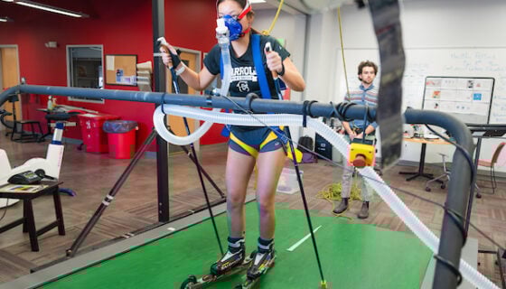 A Mountain Sports Nordic Skiing athlete roller skis on a treadmill in the HAP Lab. She is wearing a face mask that is measuring her VO2 Max.