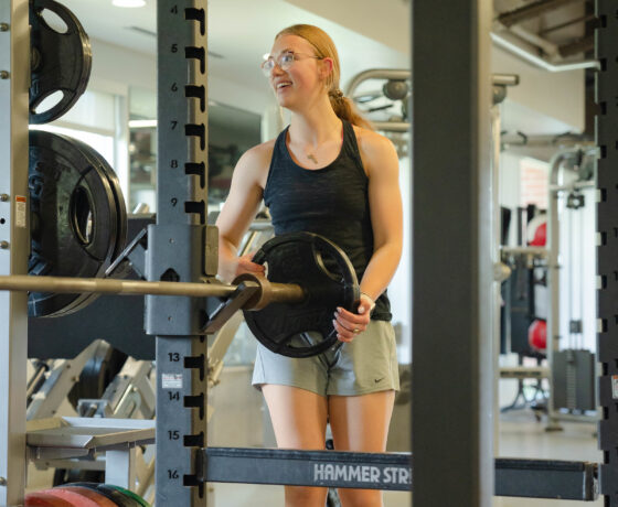 A female student takes weight off of bar at the gym.