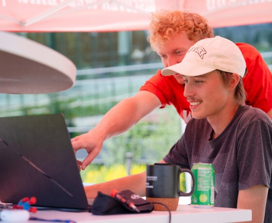 A group of students look at something on a laptop screen while running tests on their prototype sensor for RMBL.