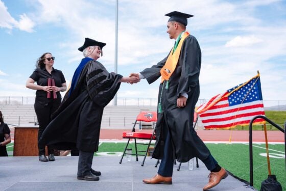 A graduate shakes Jess Young's hand.