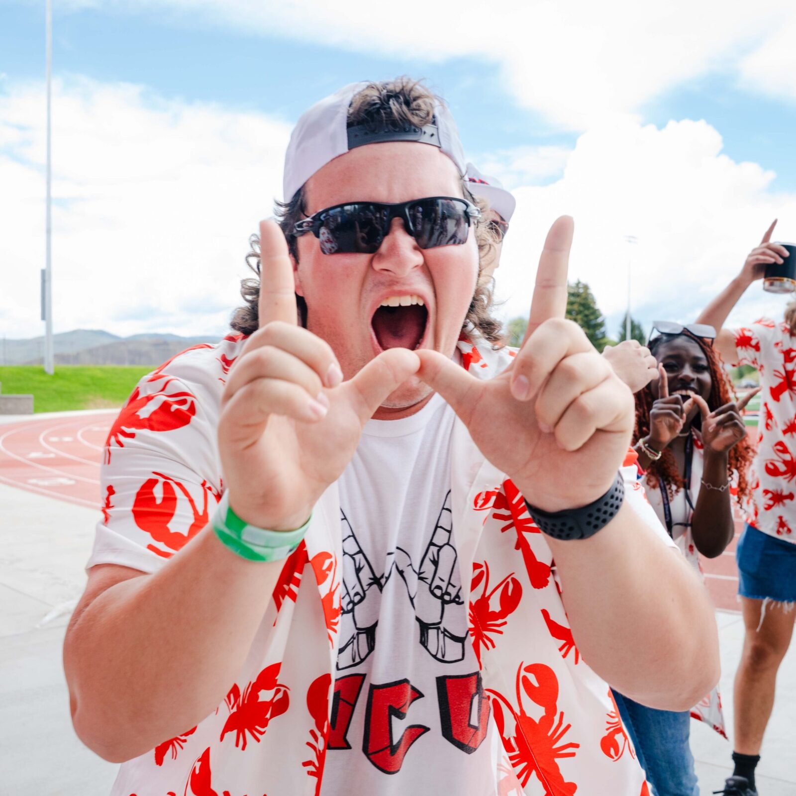 A student makes a W with his fingers and shouts while welcoming students into the Mountaineer Bowl.