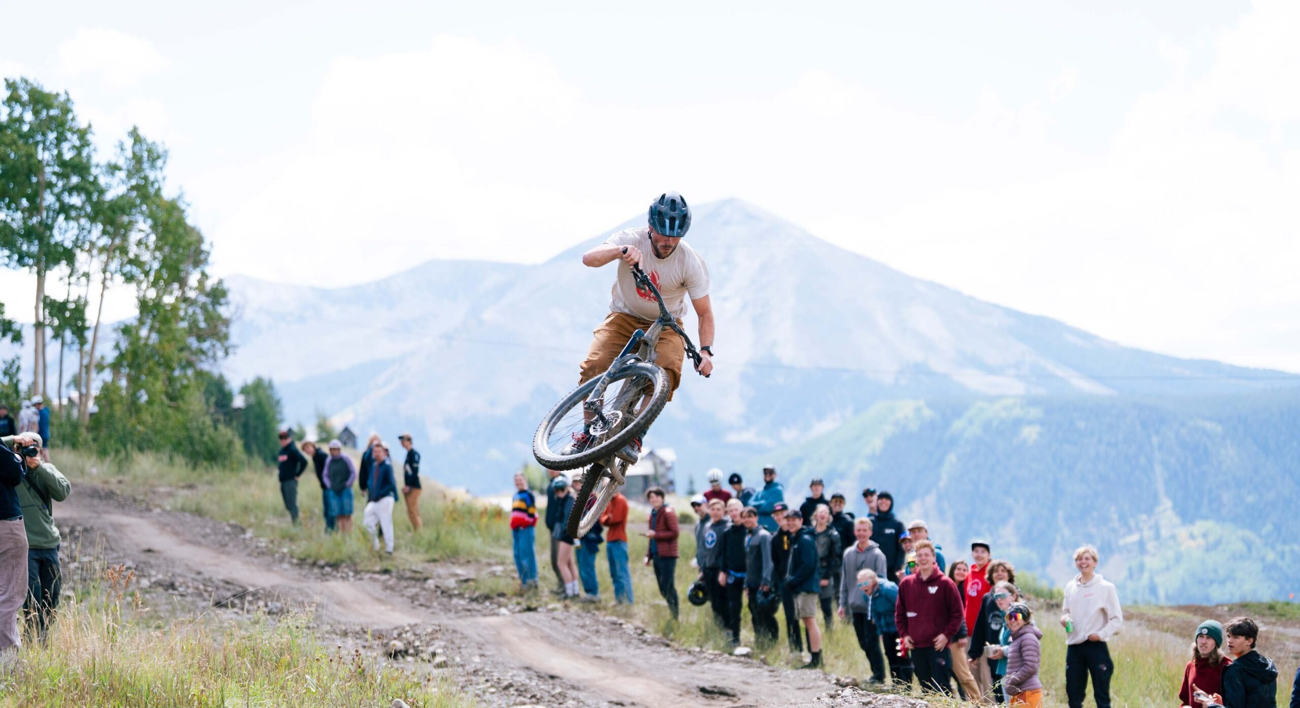 A biker does a whip off a lip while a crowd watches during the men's short track cross country bike race at Crested Butte Mountain Resort.