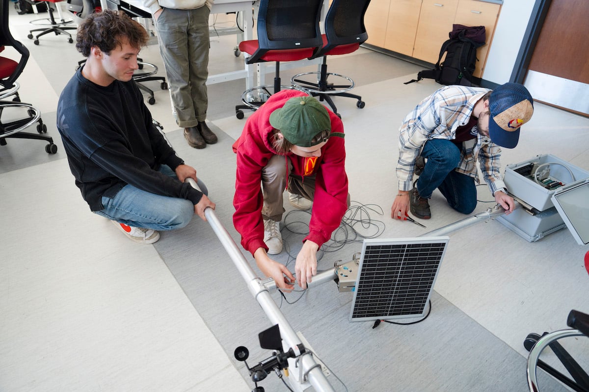 Engineering students work together to feed a wire down the metal pipe of the sensor suite they're building for the Rocky Mountain Biological Laboratory.