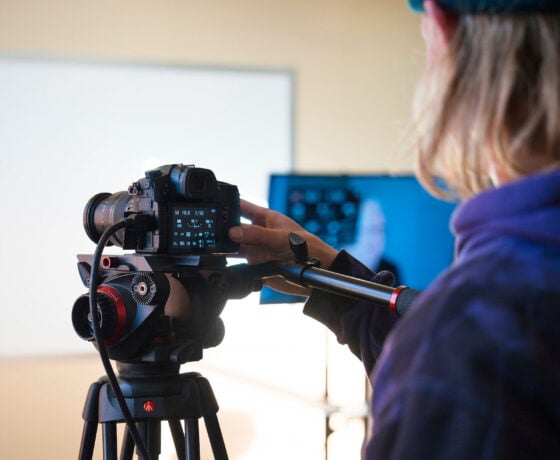 A student operates a camera during a lighting demonstration for a film class.