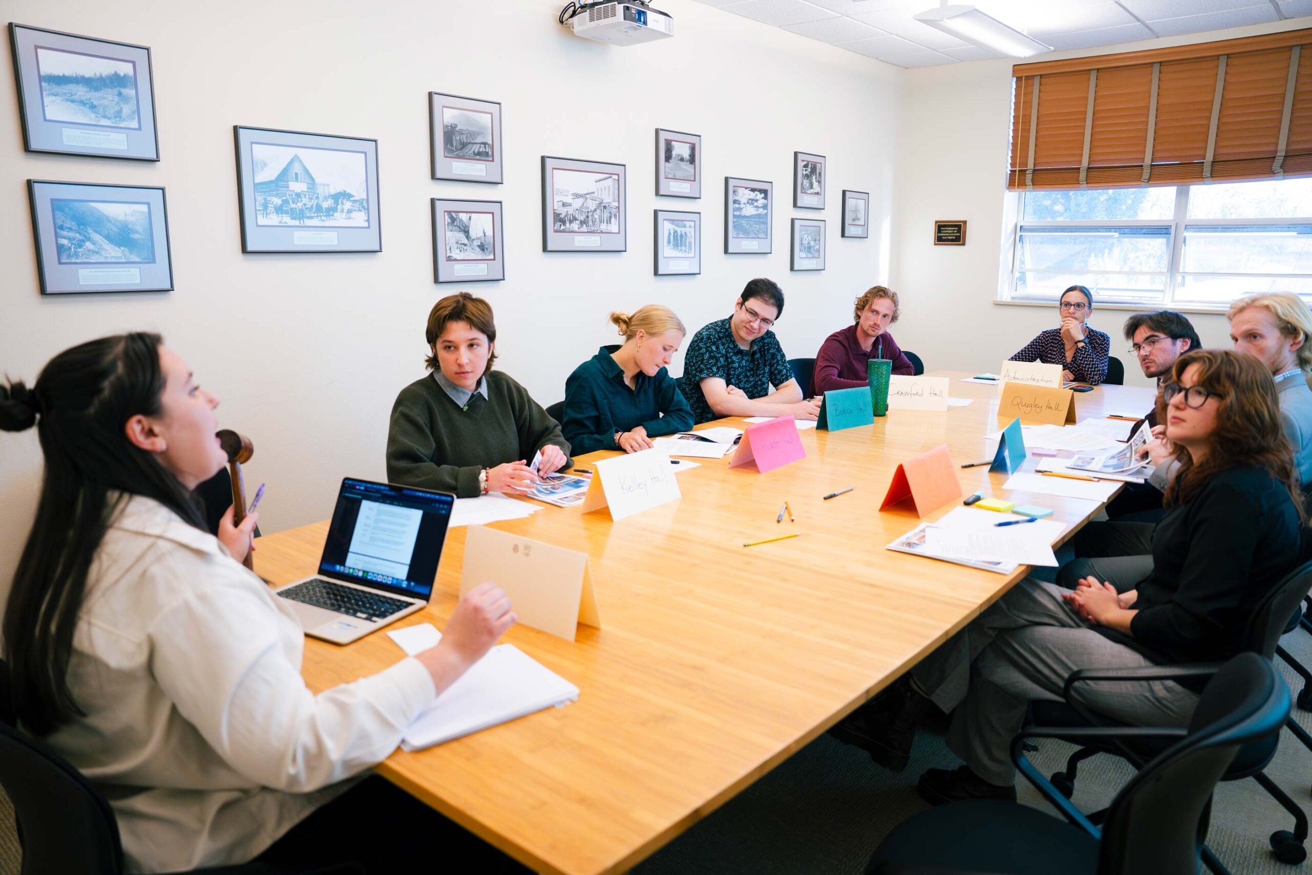 A group of students sit around a large table in Kelley Hall and listen as one person explains the rules and expectations of the Model UN simulation they're all participating in.