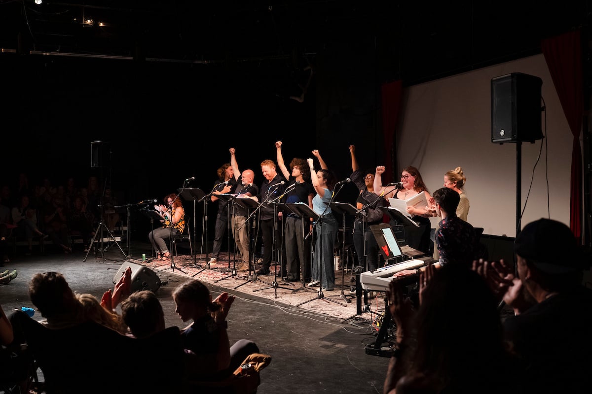 The cast of Steven Cole Hughes's 'Singletrack! The Musical' hold their fists in the air at the end of a song.