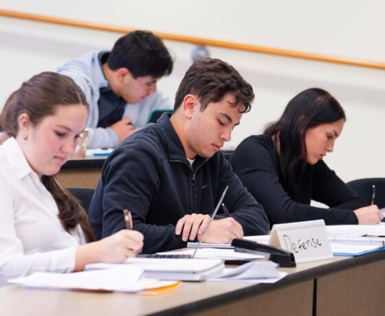 Three students acting as the defense team take notes during a mock trial scrimmage against CMU.