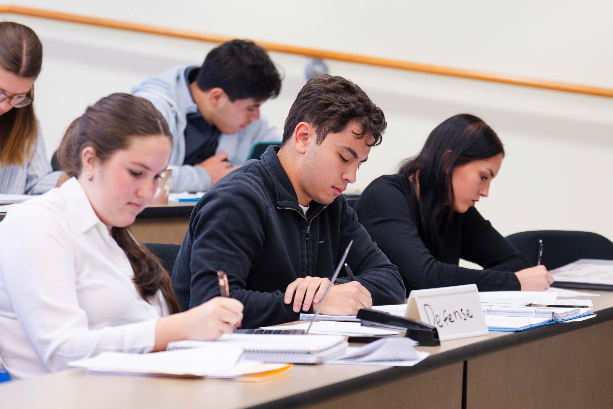 Three students acting as the defense team take notes during a mock trial scrimmage against CMU.