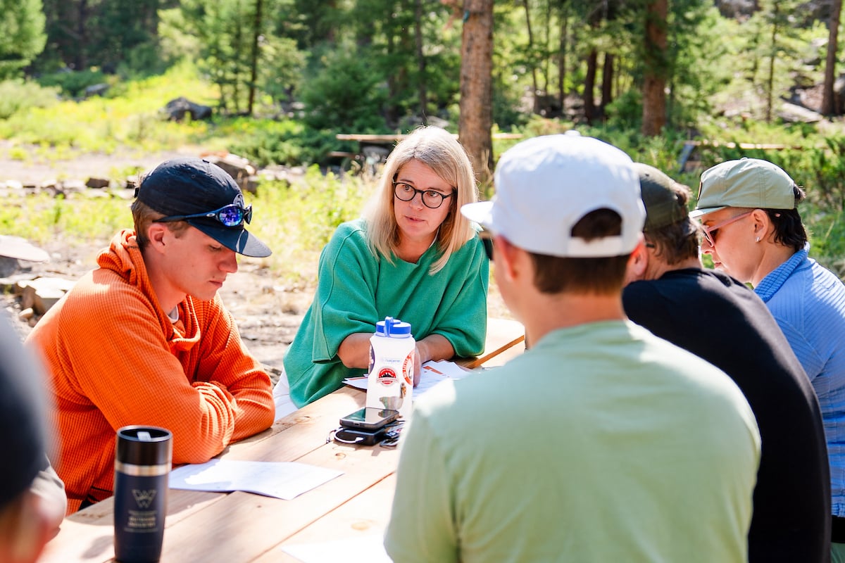 An Outdoor Industry MBA instructor lectures to a class seated outside at a picnic table