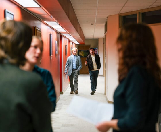 Two students walk down a hallway and talk during an informal session for a Model UN simulation.