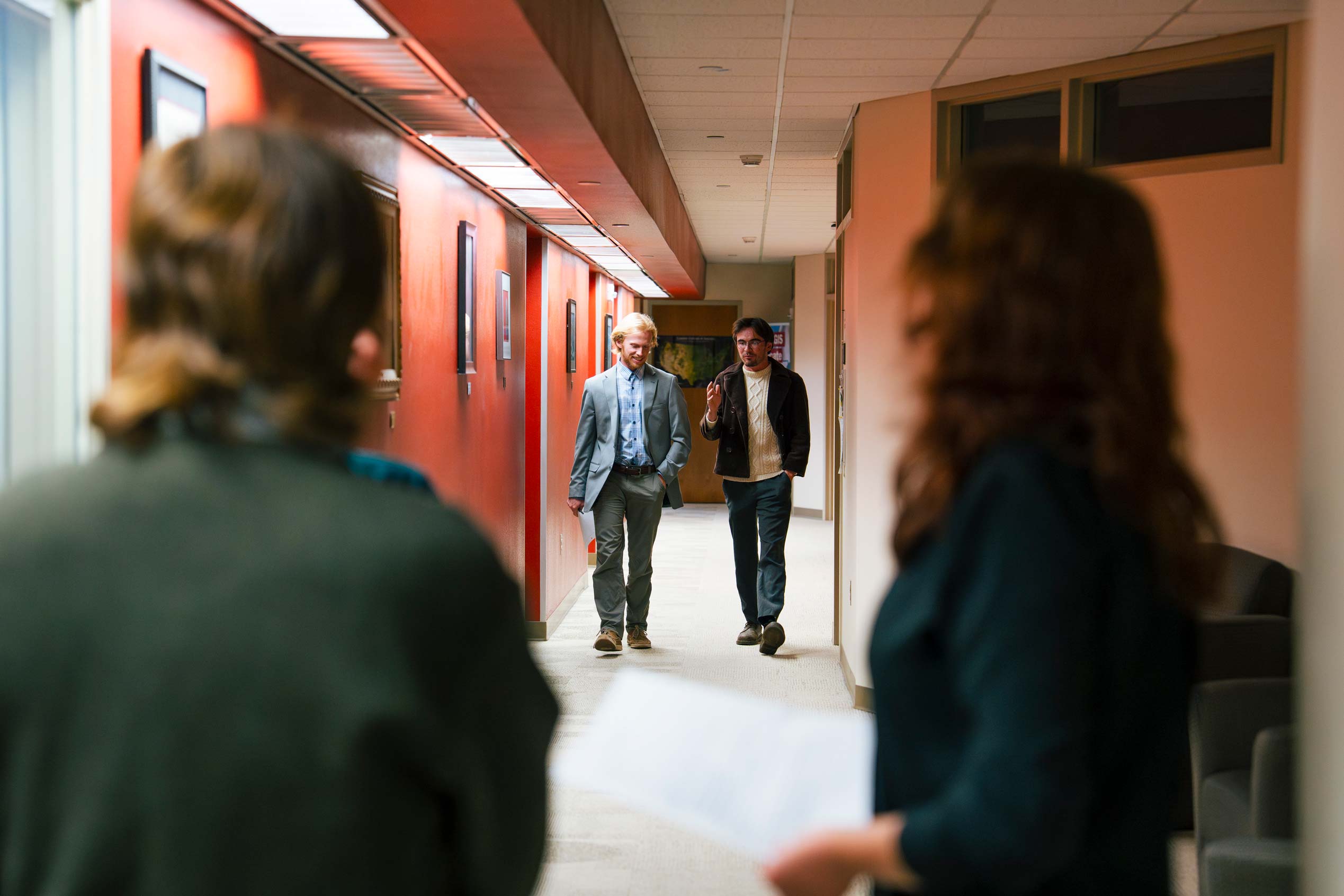 Two students walk down a hallway and talk during an informal session for a Model UN simulation.