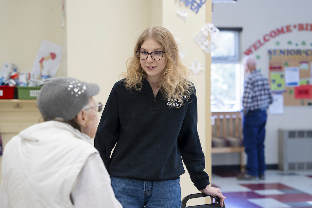 Rural Health MBS student Maddie Gregurek greets a woman as she sits down at a table for lunch at the Senior Center.