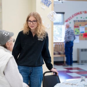 Rural Health MBS student Maddie Gregurek greets a woman as she sits down at a table for lunch at the Senior Center.