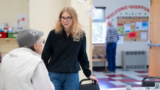 Rural Health MBS student Maddie Gregurek greets a woman as she sits down at a table for lunch at the Senior Center.