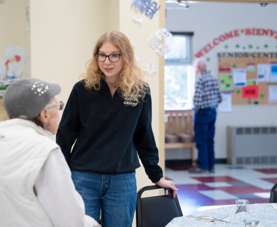 Rural Health MBS student Maddie Gregurek greets a woman as she sits down at a table for lunch at the Senior Center.