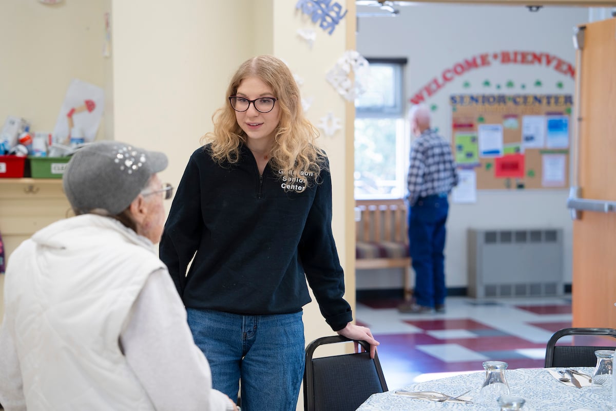 Rural Health MBS student Maddie Gregurek greets a woman as she sits down at a table for lunch at the Senior Center.