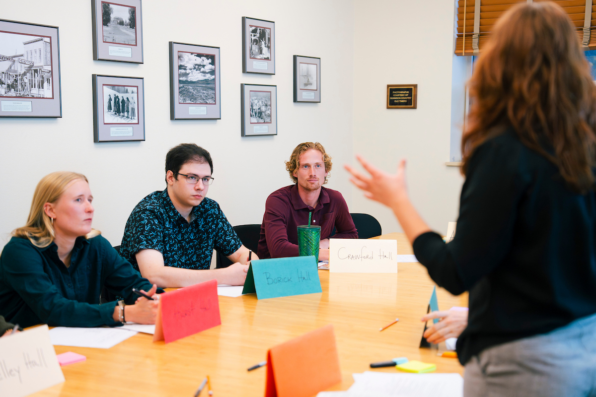 A group of students listen intently as their peer delivers a speech during a Model UN simulation.