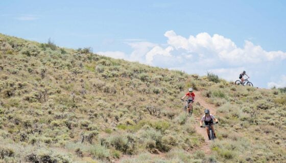 Students mountain bike down a trail in the sagebrush.