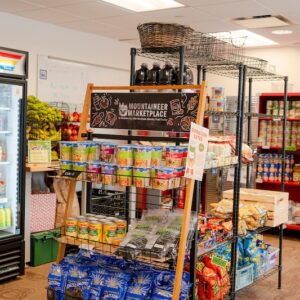 The interior of the Mountaineer Marketplace with a fridge, cabinets, and shelves full of food.
