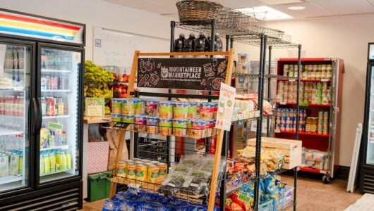 The interior of the Mountaineer Marketplace with a fridge, cabinets, and shelves full of food.