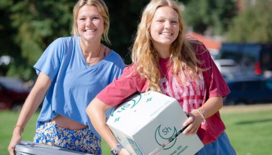 First-year students smile while holding boxes during move in