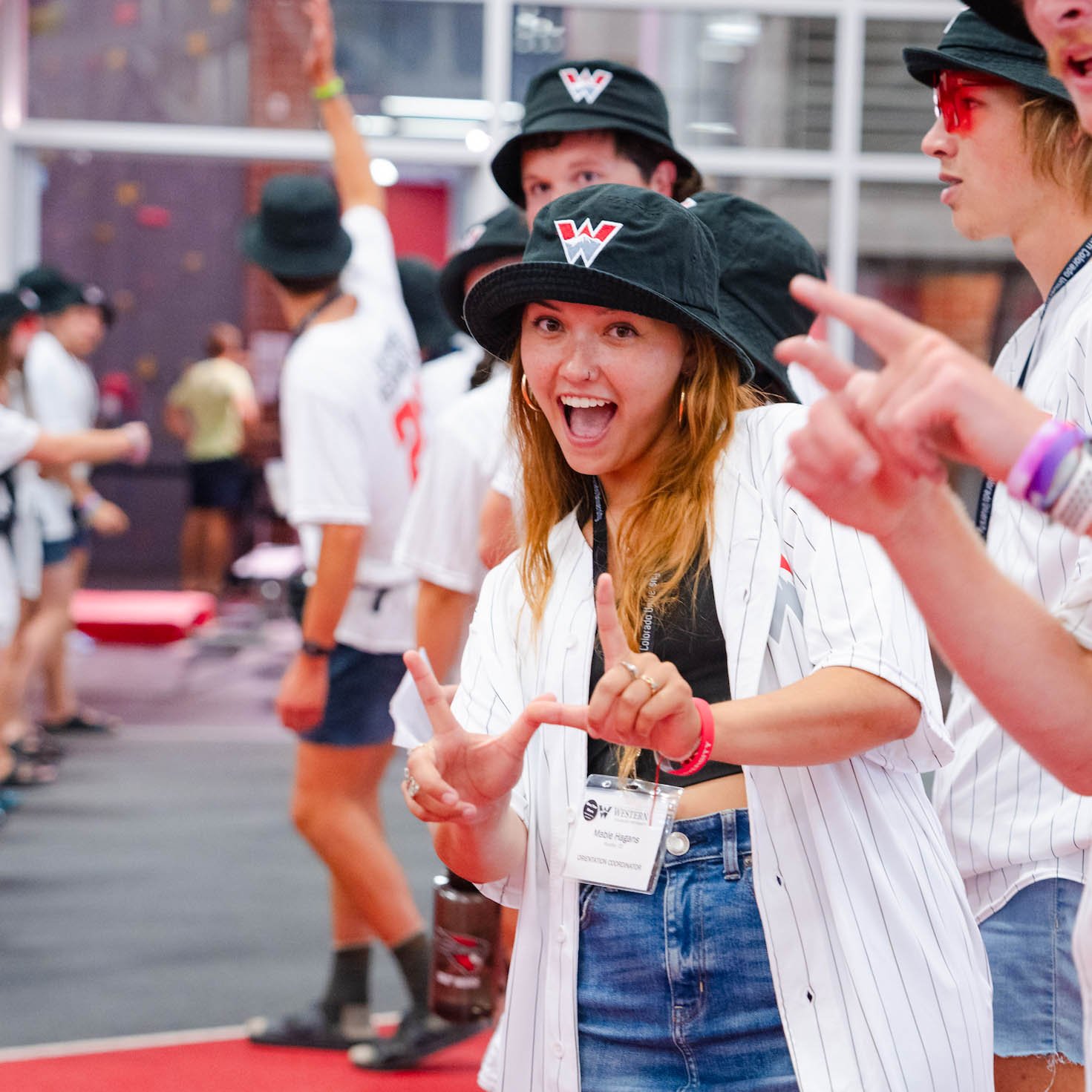 An orientation leader smiles with her hands in the shape of a "w".