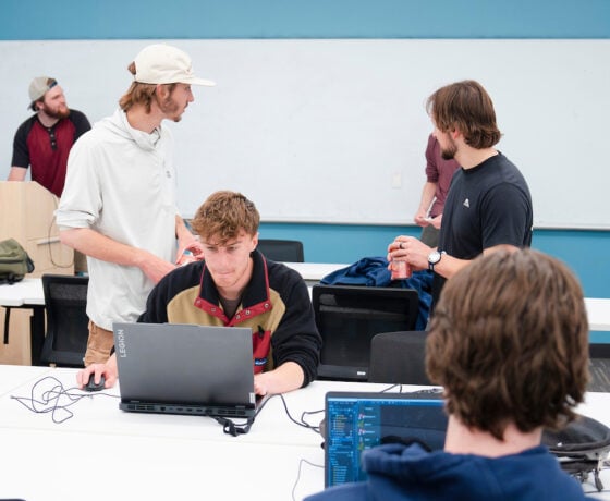 A couple of students sit at laptops and test out computer games at the CS club's game demo event.