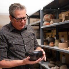 David Hyde holds and examines a bowl in the Hurst Repository.