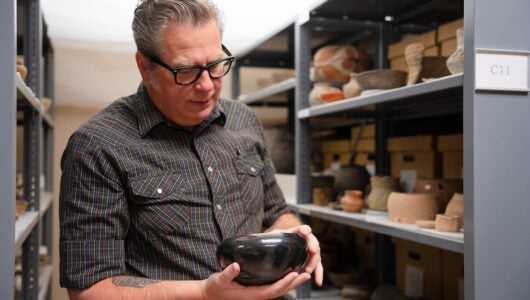 David Hyde holds and examines a bowl in the Hurst Repository.