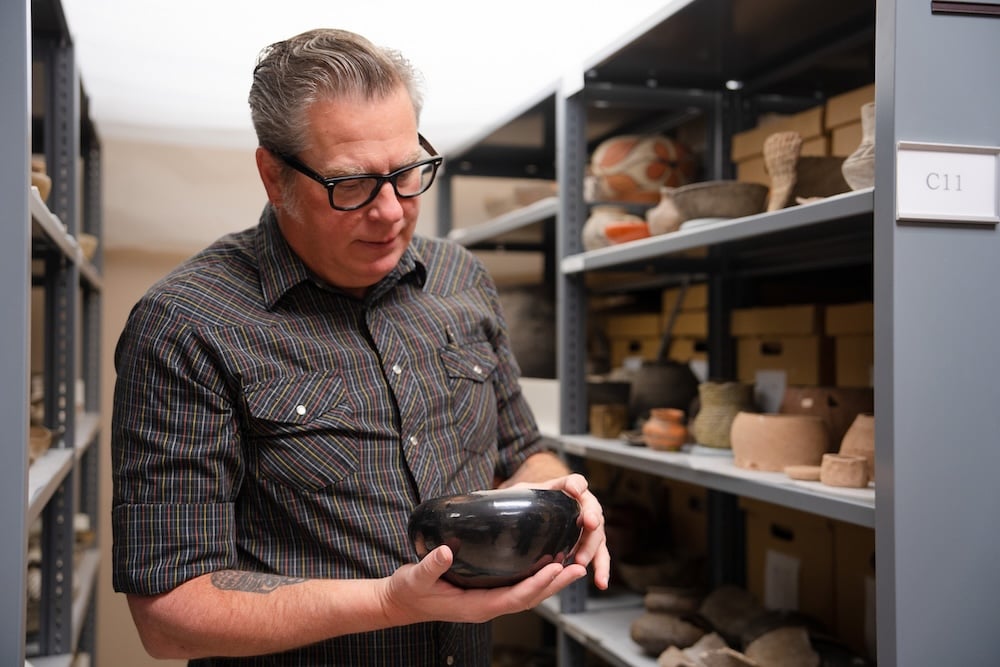 David Hyde holds and examines a bowl in the Hurst Repository.