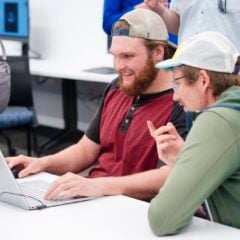 A student shows CS professor, Sam Micka, around around the computer game he built during the CS club's game demo event.