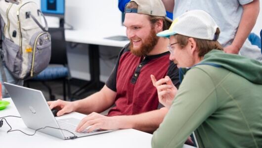 A student shows CS professor, Sam Micka, around around the computer game he built during the CS club's game demo event.