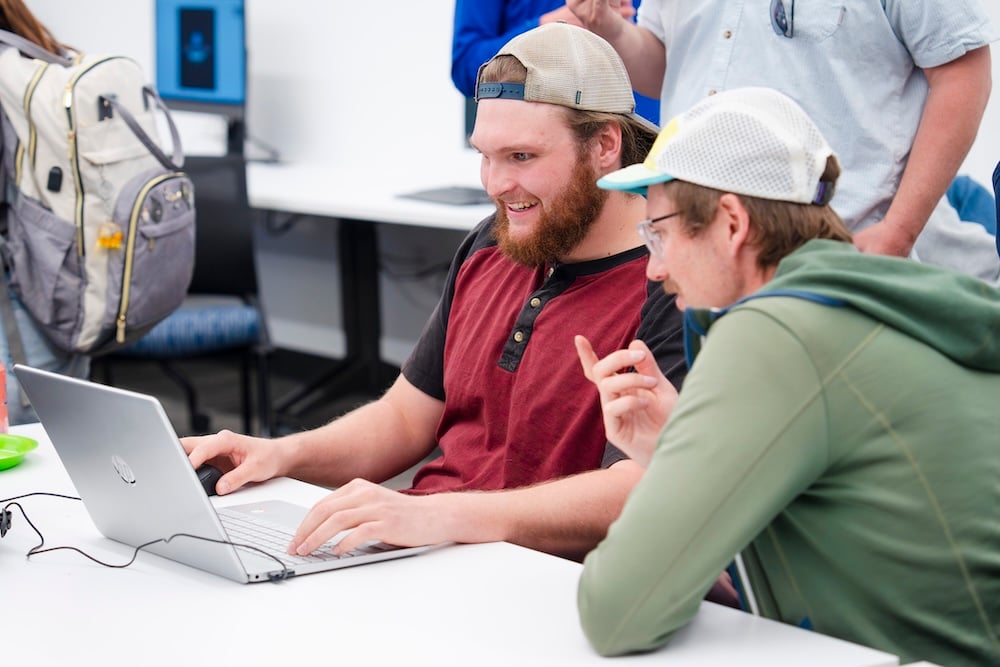 A student shows CS professor, Sam Micka, around around the computer game he built during the CS club's game demo event.