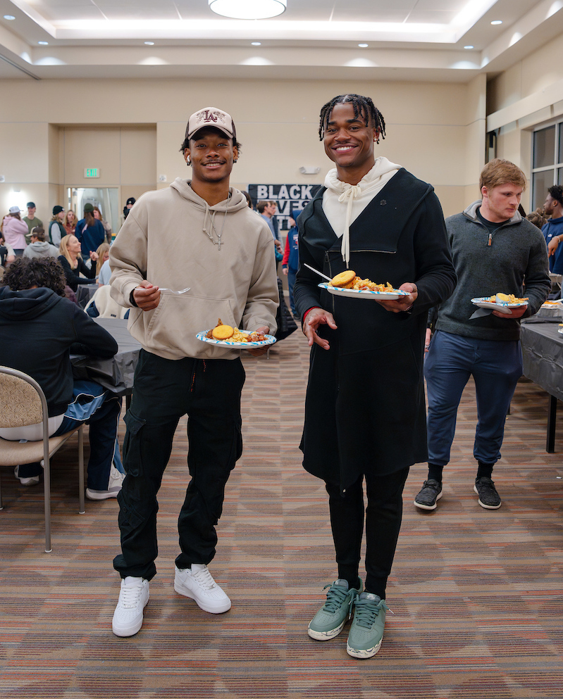 Two students hold plates in the UC Ballroom during Soul Food Night