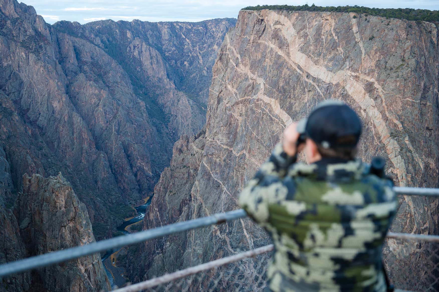 Graduate student, Cody Hinkley, glasses for big horn sheep while standing on the Painted Wall Overlook in the Black Canyon of the Gunnison National Park.