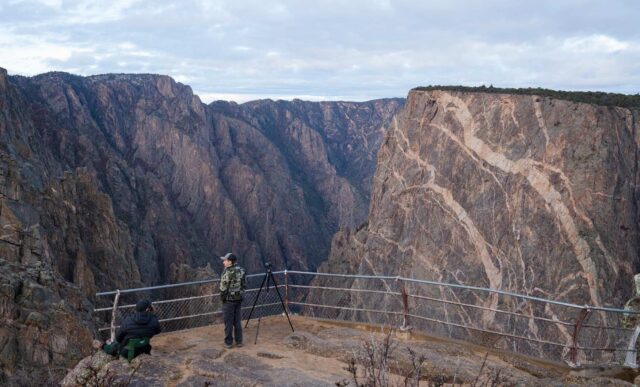 Graduate student, Cody Hinkley, takes a break from glassing for big horn sheep while standing on the Painted Wall Overlook in the Black Canyon of the Gunnison National Park.