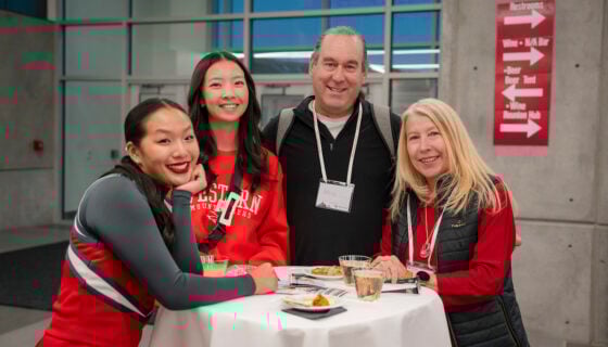 Alumni and two cheerleaders mingle at a table during the Lighting of the W Party.