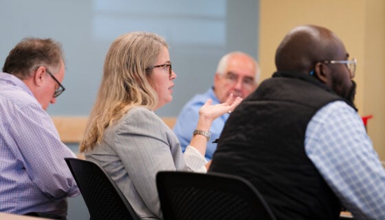 A professor for the business school asks a question after a student presentation while judging for an ethics competition.