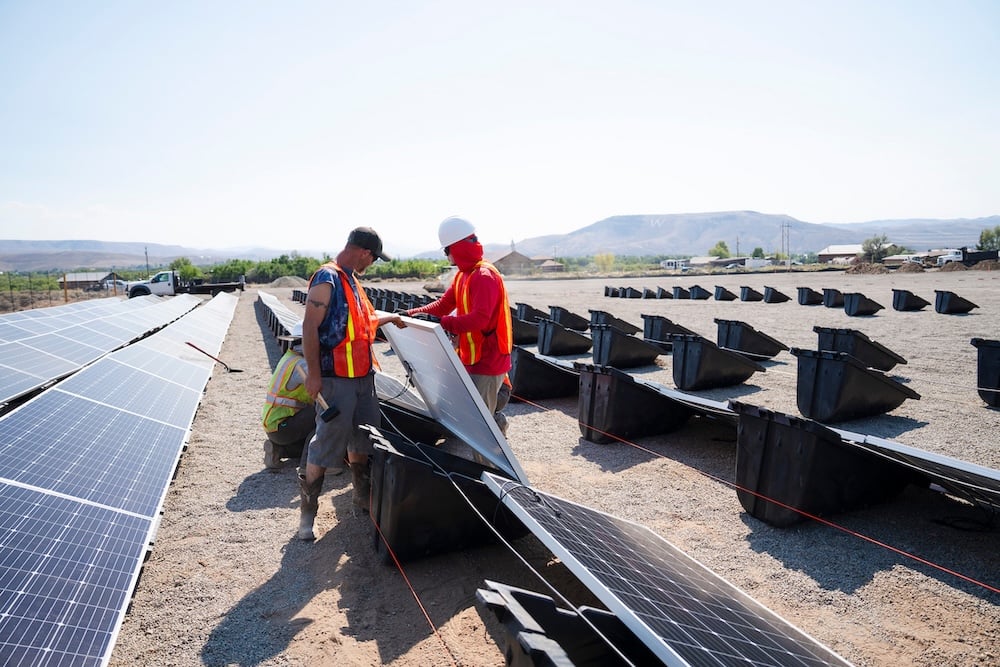 A Western student helps other employees mount a solar panel to Powerfield Energy's PowerRacks while helping build a solar array in Gunnison.