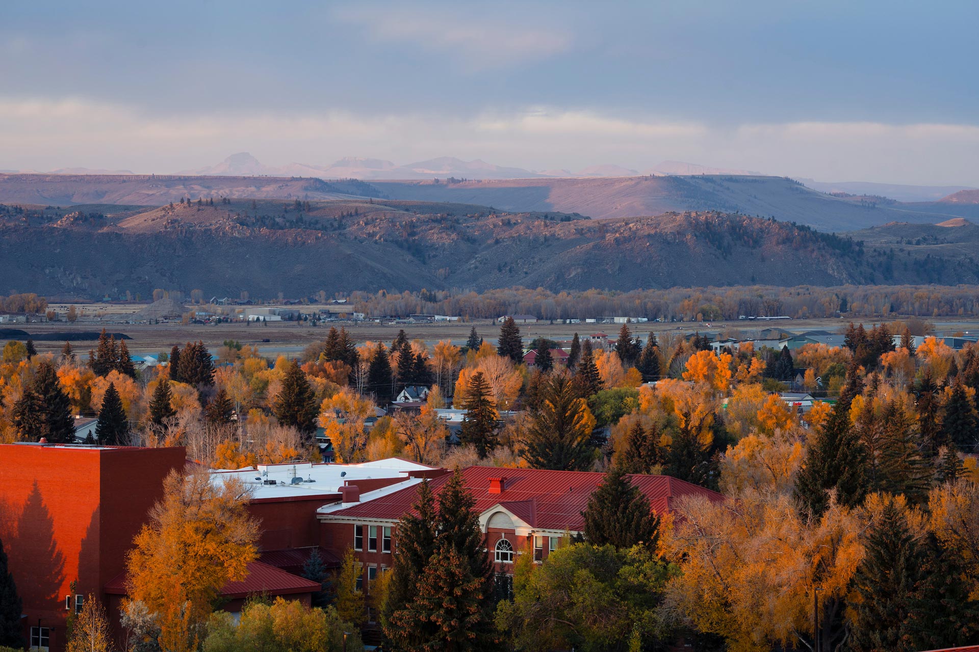 A photo during sunrise of campus in the fall showing Taylor Hall with the San Juans in the background.