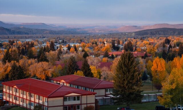 A photo of campus in the fall with Crystal Hall in the foreground, just before sunrise.
